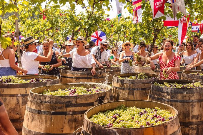 grupo de personas celebrando la fiesta de la vendimia con barriles llenos de uvas